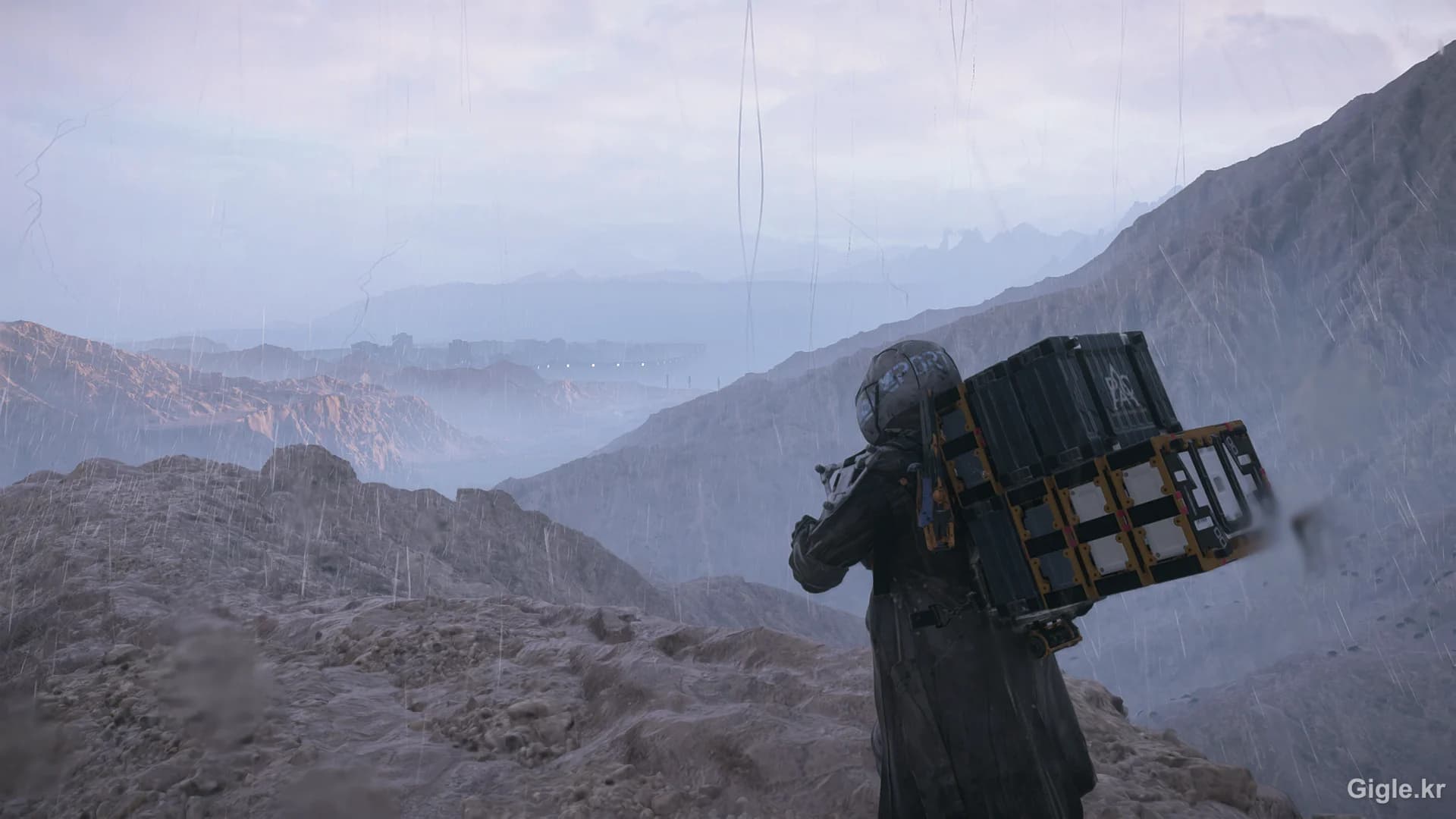 데스 스트랜딩 2 산 위에서 짐을 지고 황무지를 내려다보는 샘